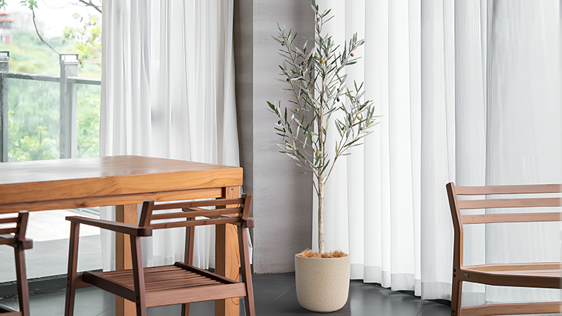Artificial olive tree in minimalist indoor setting, lifelike design for modern home decoration.