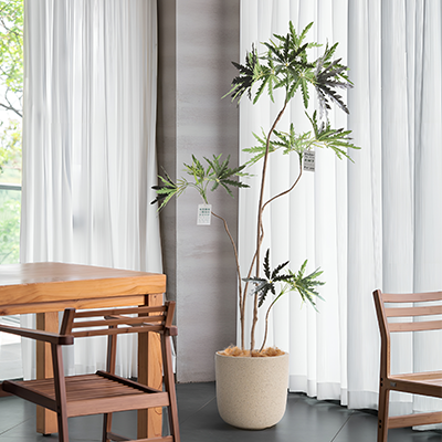 Artificial indoor tree in a beige pot, modern decor setting, suitable for offices and homes.