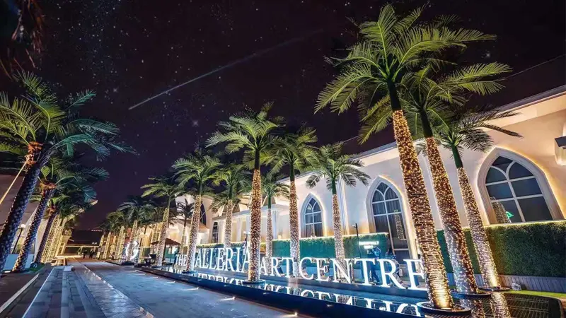 Artificial palm trees with lights outside modern building at night.