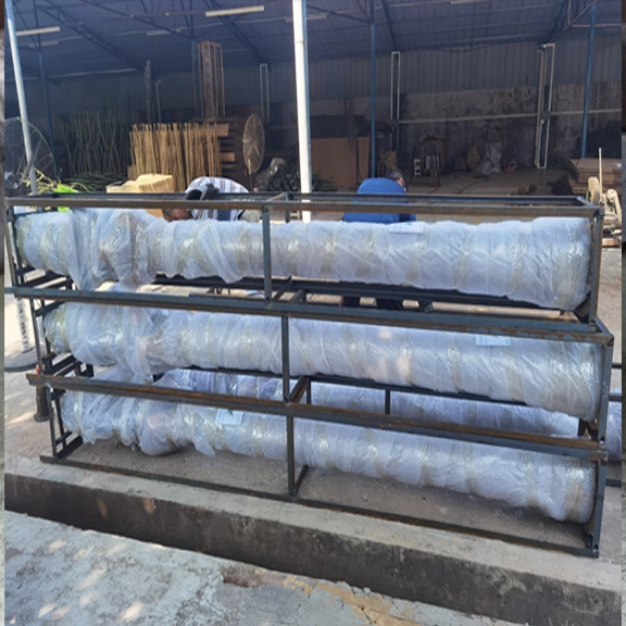 Large artificial tree trunks wrapped in protective packaging on metal racks.