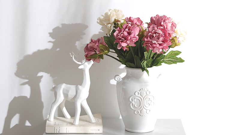 Artificial flower arrangement Elegant artificial flowers in a white decorative vase, perfect for interior decor styling.