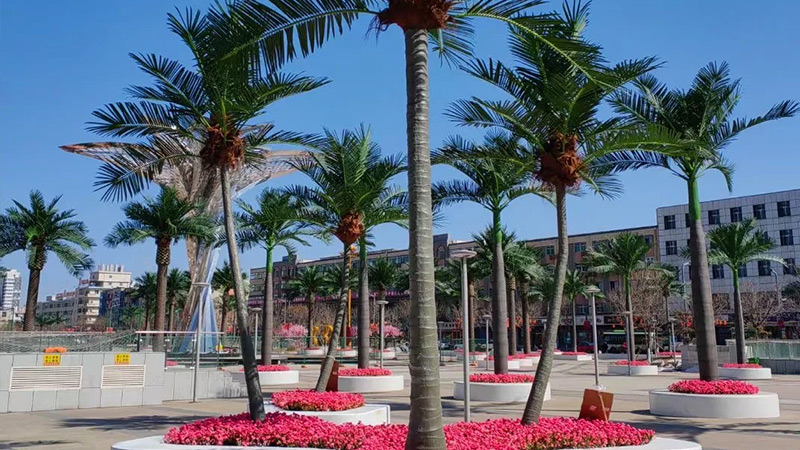 Artificial palm trees in a plaza with pink flower decorations, ideal for landscaping projects