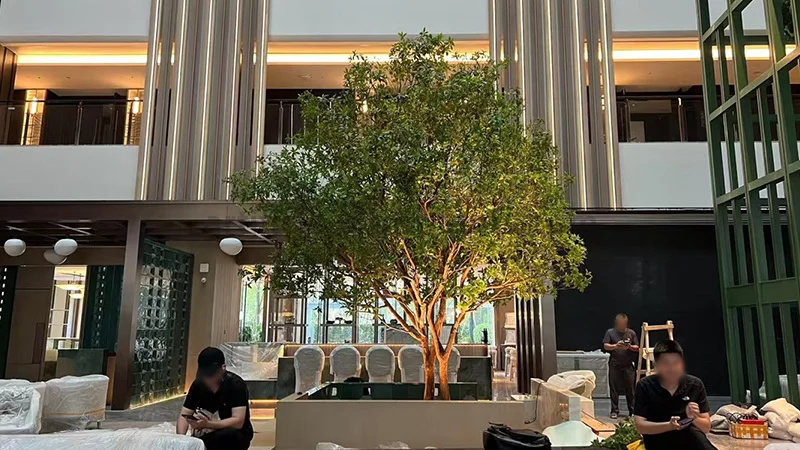 Large artificial tree with green leaves in a spacious hotel lobby or restaurant interior