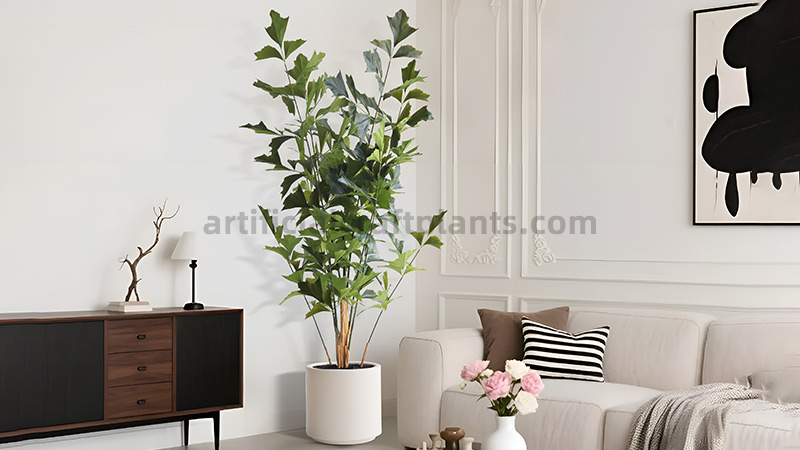 Artificial Fishtail Palm A tall, artificial fishtail palm in a white pot, situated next to a modern sofa with decorative pillows.
