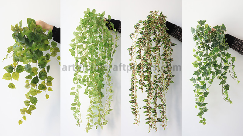 Artificial Hanging Vines Four different styles of artificial hanging vine plants held by a person against a white background.