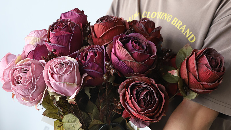 Artificial dark red rose bouquet Close-up of a person holding a bouquet of artificial dark red and pink roses