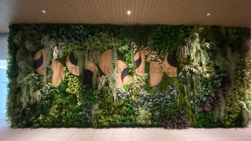 Decorative Artificial Green Wall Large artificial green wall with decorative wooden and black circular elements.