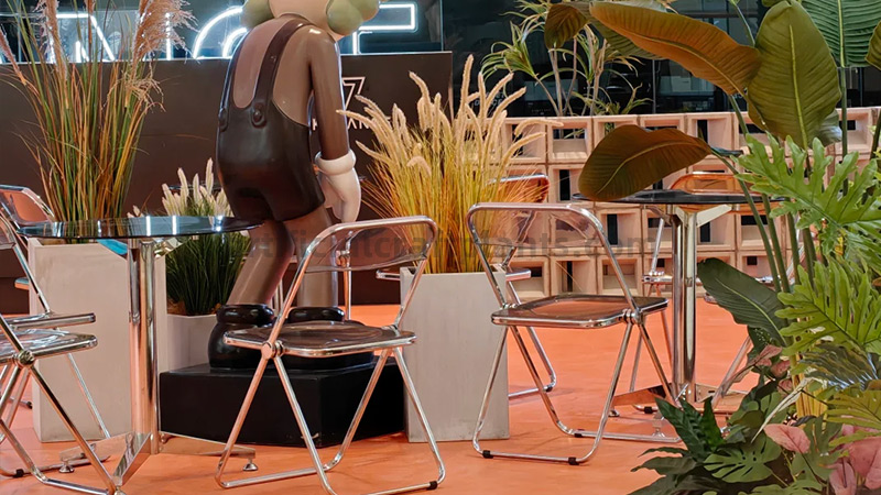 Indoor Artificial Plant Display Indoor artificial plant display with tables, chairs, and a large doll.